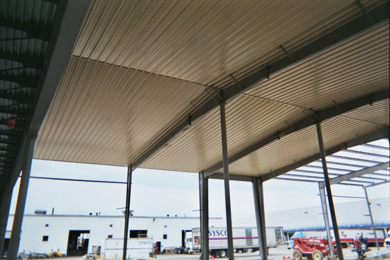 Steel building erection with red iron frames and crew on site