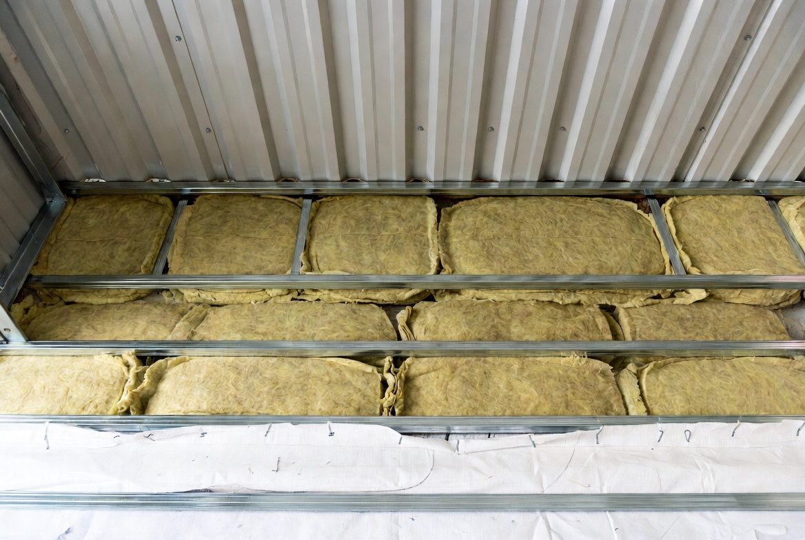Multi-layer fiberglass insulation filling purlin cavities under metal roof