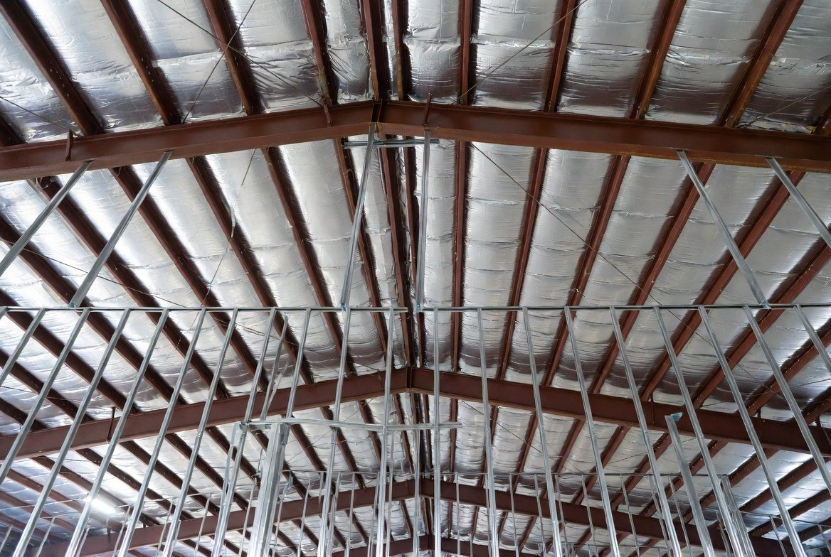 Metal building roof structure with reflective insulation under panels