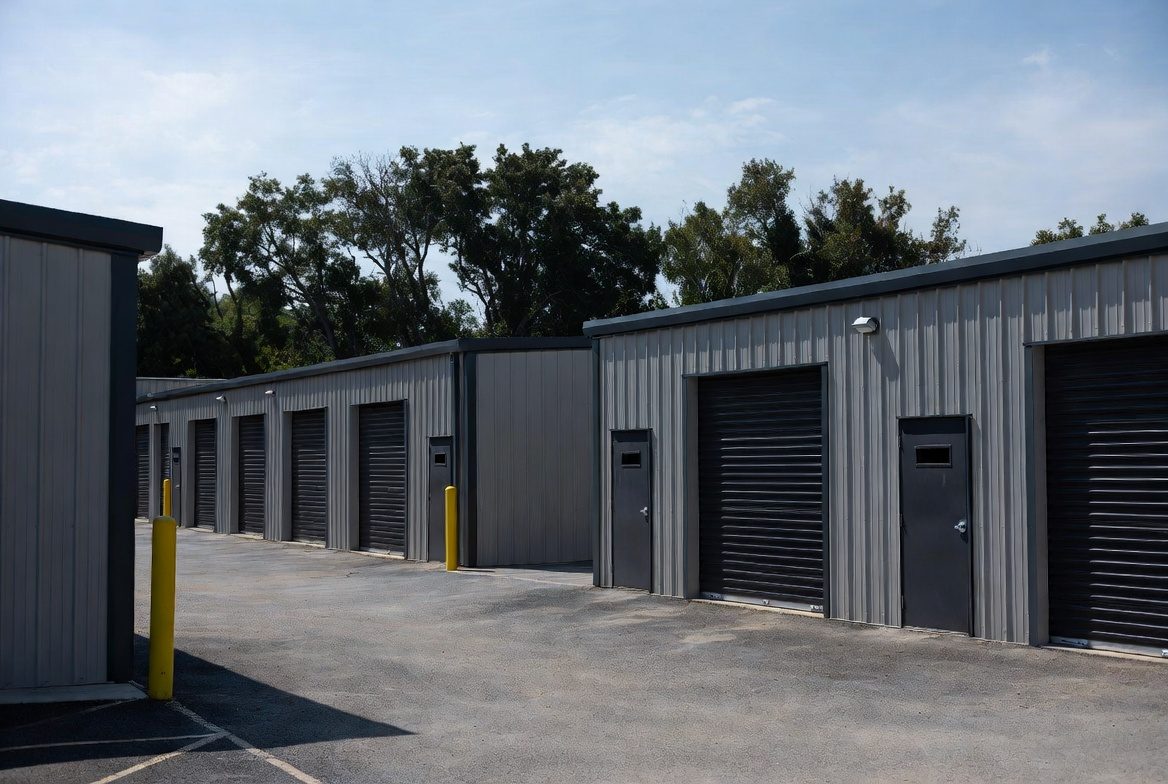 Gray mini storage complex with black roll-up doors and paved drive